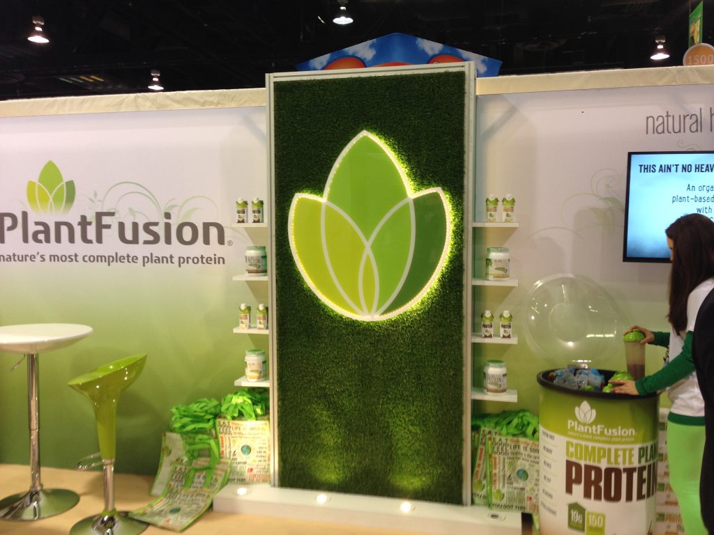 Trade show booth with a person on the right side, reaching into a drink barrell